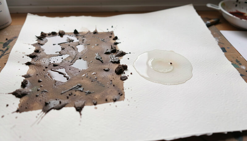 A sheet of watercolor paper showing a muddy overworked patch beside a clean hard-edged shape and a bloom.